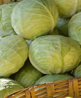 a basket filled with cabbage next to a pile of green apples