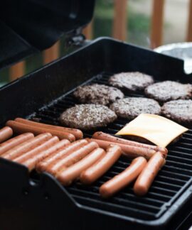 person standing in front grill grilling sausage