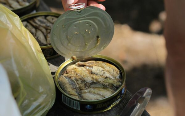 person holding clear glass jar with yellow powder