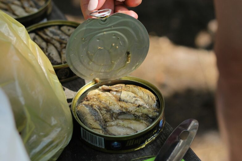 person holding clear glass jar with yellow powder