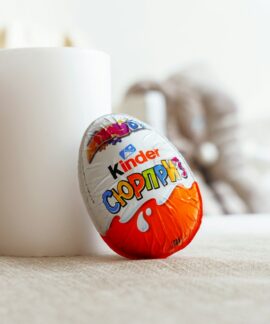 a white cup sitting next to an orange and white egg