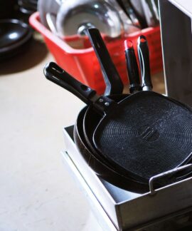 black and red handled frying pan on white table