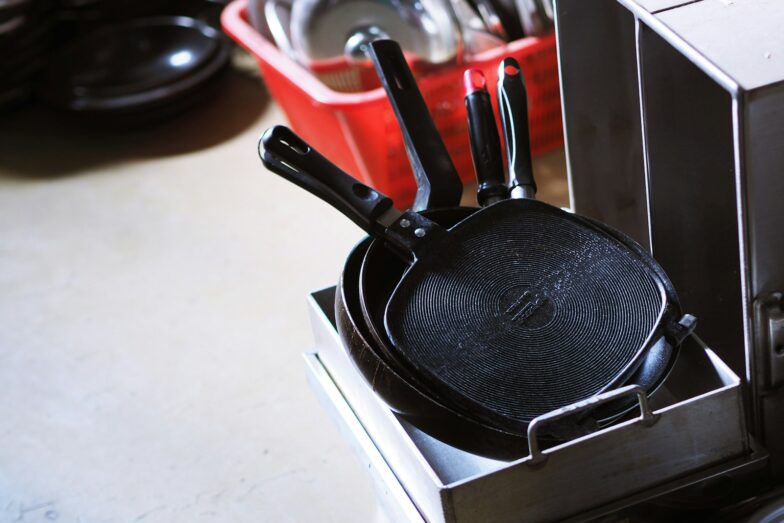 black and red handled frying pan on white table