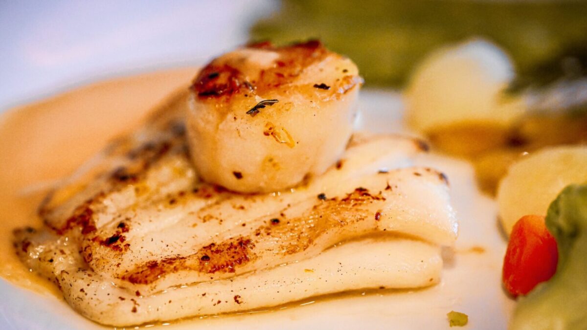 Delicious pan-seared scallops and grilled fish served with vegetables, ideal for culinary enthusiasts.
